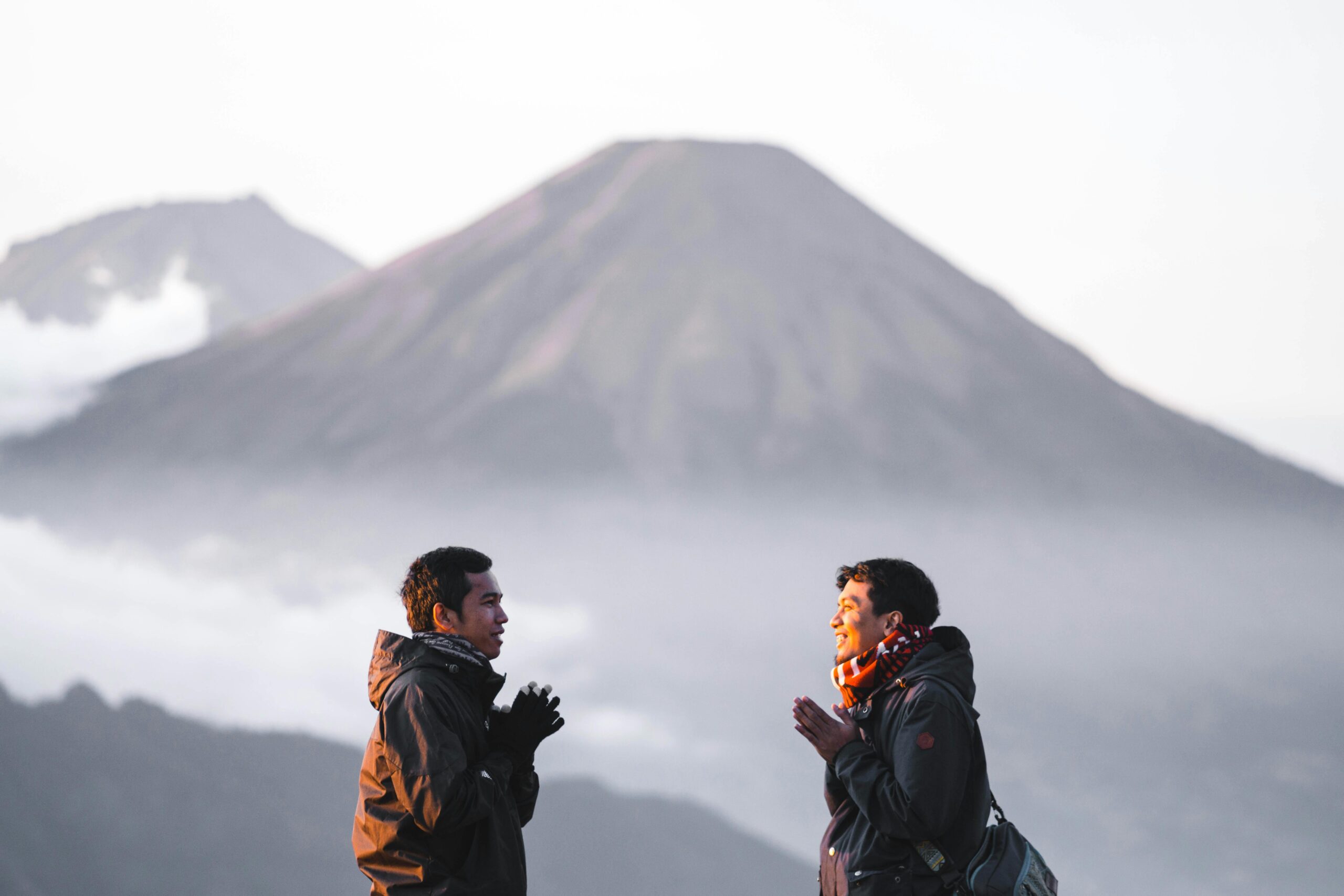 Two men enjoy a scenic hike on Indonesia's Gunung Prau, surrounded by misty mountains at sunrise.